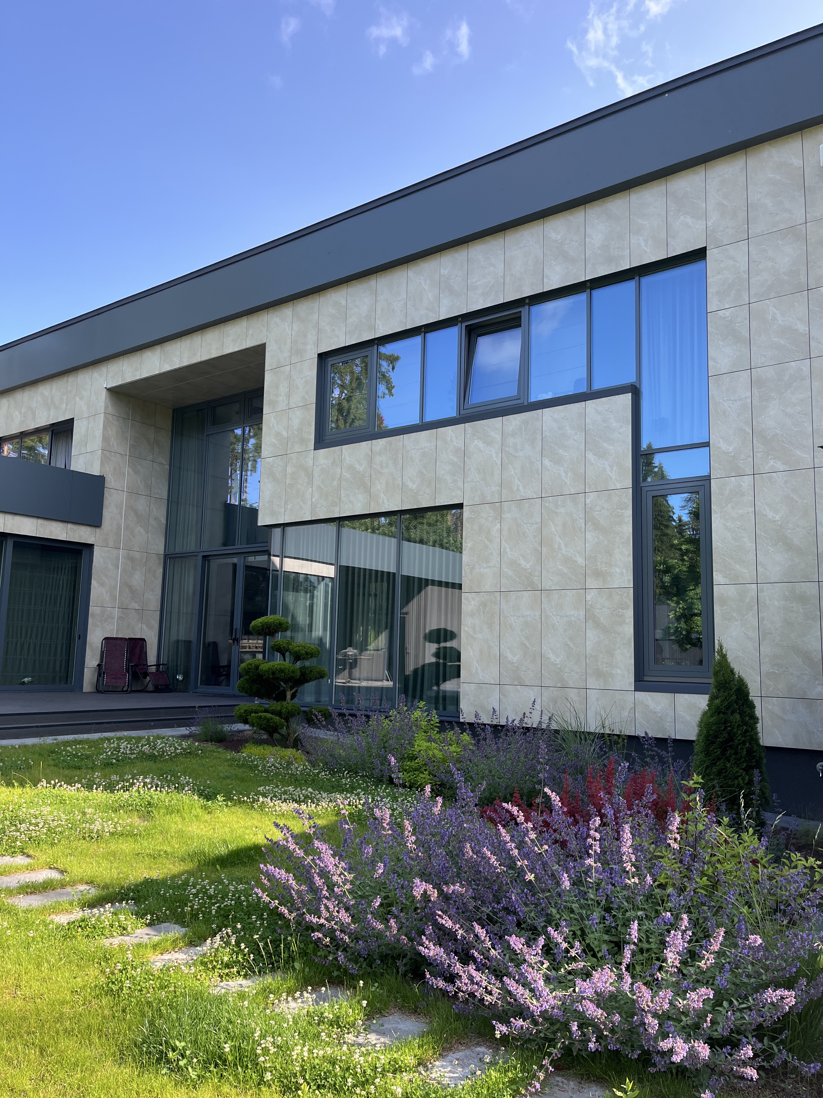 Mūsdienīga privātmāja ar lieliem tumšiem logiem un stiklojumu